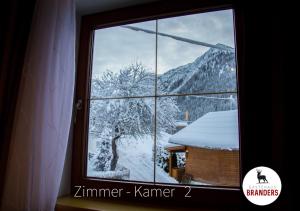 a window with a view of a snow covered mountain at Gästehaus Branders in Namlos