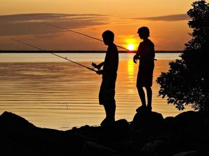 two people fishing in the water at sunset at 6 person holiday home in Hemmet in Falen