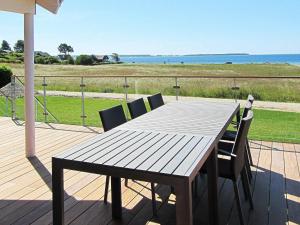 エーベルトフトにある24 person holiday home in Ebeltoftの海を望むデッキ(木製テーブル、椅子付)
