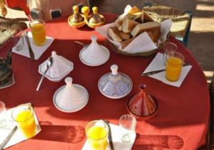 a red table with plates and pitchers and glasses of orange juice at Camp Cheri Beri in Mhamid