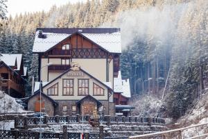 duży drewniany dom w śniegu z drzewami w obiekcie Ganz SKI Lift 5 w mieście Bukowel