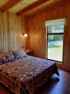 um quarto com uma cama e uma janela grande em Paraíso Liumalla Lodge em Villarrica