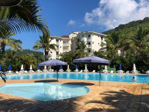 a pool at a resort with umbrellas and chairs at Apto diferenciado em Ubatuba in Ubatuba