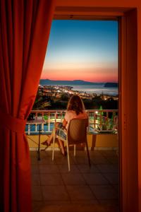 a woman sitting in a chair on a balcony watching the sunset at Eliros Studios in Stalos