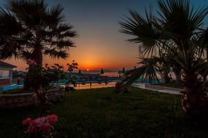 a sunset over a swimming pool with palm trees at Eliros Studios in Stalos