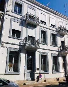 - un bâtiment blanc avec balcon dans une rue dans l'établissement LES CHAMBRES D'HOTES DU PALAIS, à Douai