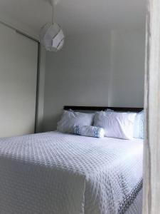 a bed with white sheets and pillows in a bedroom at APARTAMENTO FRENTE MAR com vista fantástica in Balneário Camboriú