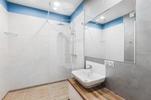 La salle de bains blanche est pourvue d'un lavabo et d'une douche. dans l'établissement CityApartments Kyiv Akademmistechko, à Kiev