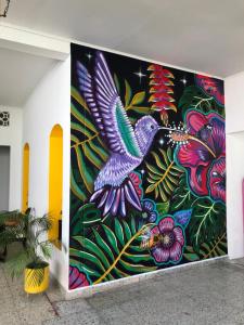 a wall with a mural of a bird and flowers at Casa de Luna in La Dorada