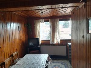 Cette chambre dispose d'une table, d'une télévision et d'une fenêtre. dans l'établissement Guest House Terziiski, à Koprivchtitsa