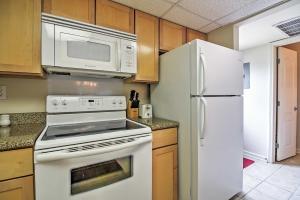 - une cuisine avec des appareils blancs et des armoires en bois dans l'établissement Ocean Springs Condo in Waterfront Resort!, à Ocean Springs