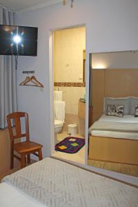 una camera da letto con specchio, letto e sedia di Residencial Paranhos a Porto