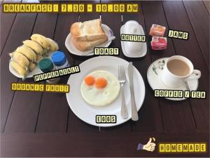 a table with plates of breakfast food and a cup of coffee at Jim Guesthouse in Kanchanaburi City