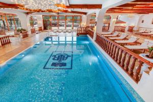 a pool in a hotel with chairs and tables at Aurelius Imparatul Romanilor Hotel & SPA in Poiana Brasov