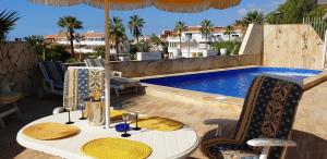 einen Tisch mit Stühlen und einen Sonnenschirm neben einem Pool in der Unterkunft Sunny house with private pool and sea view in Adeje