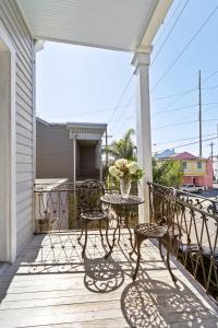 un porche con 2 sillas y una mesa con un jarrón de flores en Montgomery House en Nueva Orleans