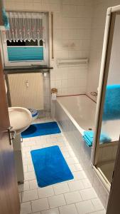baño con bañera, lavamanos y alfombra azul en Ferienwohnung Schäfer, en Landwehrhagen