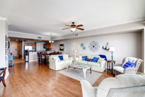 a living room with white furniture and a ceiling fan at Sleek Gulfport Condo with Ocean Views and Pool Access! in Gulfport