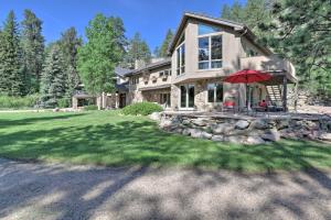 Casa grande con patio de piedra y sombrilla roja en Stunning Evergreen Mountain Home on Private Stream, en Evergreen