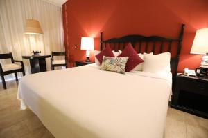 a bedroom with a large white bed with red walls at Hotel Montetaxco in Taxco de Alarcón