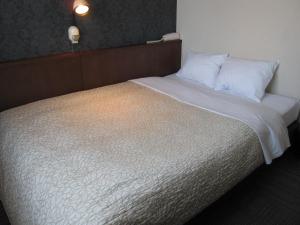 - un lit avec des draps et des oreillers blancs dans l'établissement Toyohashi Station Hotel / Vacation STAY 65494, à Toyohashi