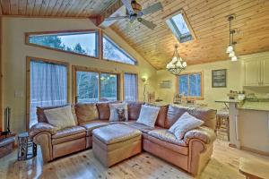a living room with a brown couch and some windows at Jewett Cabin with Viewing Deck - 10 Mins to Skiing! in Jewett