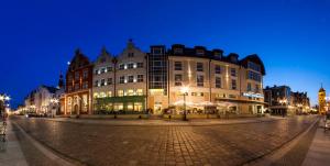 a large building on a city street at night at Focus Hotel Premium Elbląg in Elblag