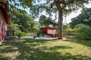 a yard with a red house and a tree at August Schmidt Fredericksburg Cottage with Hot Tub in Fredericksburg