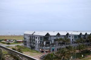 an apartment building with palm trees in front of the ocean at Apartment The Sails in Durban