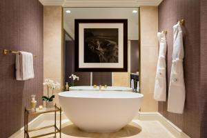 a bathroom with a large tub and a mirror at Rosewood Mansion on Turtle Creek in Dallas