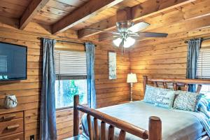 a log cabin bedroom with a bed and a ceiling fan at Lake Broward Cabin with Private Boat Launch and Dock! in Satsuma