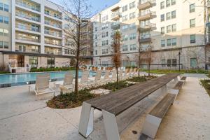 a wooden bench in front of a pool with buildings at Kasa Arlington Dallas in Arlington