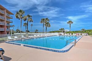 uma piscina num resort com cadeiras e palmeiras em Oceanfront Cocoa Beach Condo with View Walk to Pier em Cocoa Beach