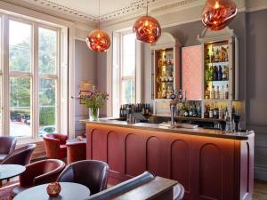 a bar in a restaurant with tables and chairs at Cotswold Grange in Cheltenham