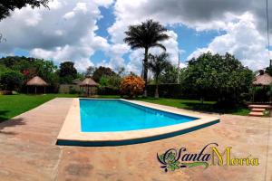 a swimming pool in a yard with a palm tree at Hotel Santa María Homun in Homún