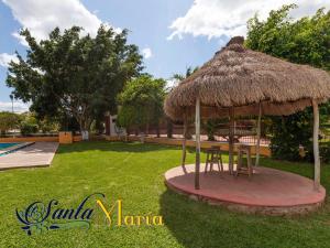 a table and chairs under a straw umbrella at Hotel Santa María Homun in Homún