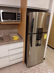 einen Kühlschrank aus Edelstahl in einer Küche mit einer Mikrowelle in der Unterkunft Condominio La Victoria, Departamento en Cuenca 1 in Cuenca