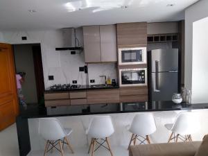 cocina con sillas blancas y encimera con nevera en Flat top Guarujá, en Guarujá