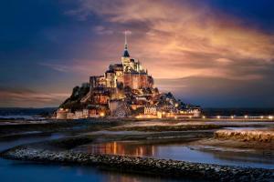 a castle on an island in the water at night at Altos Hotel & Spa in Avranches