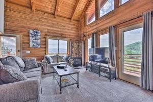 a living room with a couch and a tv and windows at Spacious Hilltop Cabin with Deck and Scenic Views! in Eden