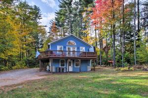 a blue house with a deck in the woods at Bethel Chalet with Hot Tub 3 Miles to Sunday River! in Bethel