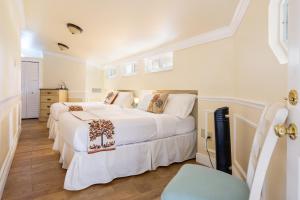 two beds in a bedroom with white walls and wooden floors at Home by Beach 5 - The Treehouse in Naples