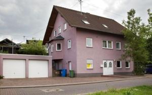 duży fioletowy dom z dwoma białymi drzwiami garażowymi w obiekcie Holzfeld w mieście Boppard
