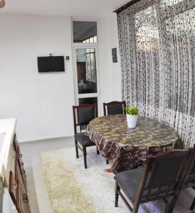 ein Wohnzimmer mit Tisch und Stühlen und einem Fernseher in der Unterkunft Уютен апартамент в Търговище - 2 спални и кухня in Targowischte