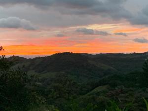 a sunset in the mountains with trees in the foreground at Globi lodge #2 in Monteverde Costa Rica