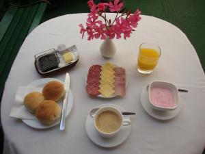 a white table with breakfast foods and a cup of coffee at Hotel Las Flores in Santiago