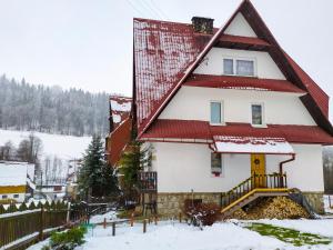 una casa con techo rojo en la nieve en Apartament u Helenki, en Groń