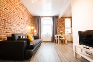 uma sala de estar com um sofá e uma parede de tijolos em UNO Apartaments em Katowice