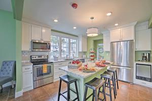 a kitchen with white cabinets and a island with bar stools at Downtown Branson Home with Pool Near The Landing! in Branson