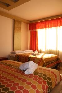 a hotel room with two beds with towels on them at Hostal Dugan in Baños